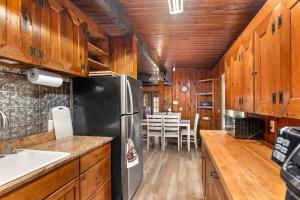 eine Küche mit Holzschränken und einem schwarzen Kühlschrank in der Unterkunft Tree Canopy Oasis in East Quogue