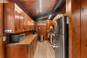 eine Küche mit Holzschränken und einem Edelstahlkühlschrank in der Unterkunft Tree Canopy Oasis in East Quogue