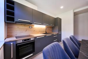 a kitchen with black cabinets and blue chairs at Luče Holiday Apartment in Luče