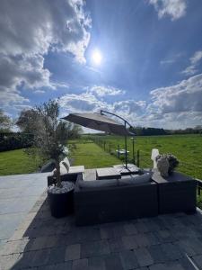 a patio with a couch and an umbrella at Charmante maison rénovée in Fernelmont