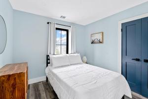 ein weißes Schlafzimmer mit einem Bett und einem Fenster in der Unterkunft Marble & Sun in Hampton Bays