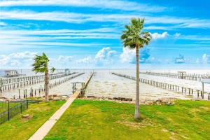 a palm tree next to a beach with a pier at Reel Paradise in Bacliff