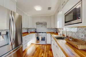 a kitchen with white cabinets and a stainless steel refrigerator at Waterfront Hideaway in La Marque +12 photos