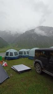 a group of tents and a jeep parked in a field at Nomad's Nest Camp in Wāmpor