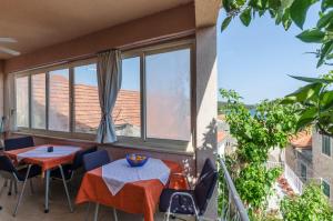a balcony with two tables and chairs and windows at Rooms Roza in Vrboska