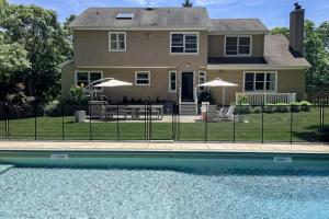 a house with a fence around a swimming pool at Hamptons Hideaway in Hampton Bays