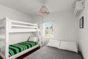 a white bedroom with a bunk bed and a ladder at 10 Cayuga in Ocean Bay Park +11 photos