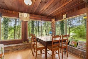 a dining room with a table and chairs and windows at Cozy waterfront cabin with fire pit in Old Hickory