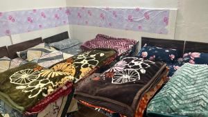 a room with four beds with colorful blankets and pillows at Jhalaram house in Kedārnāth