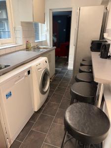 a kitchen with a washing machine and four stools at Hangover Hotel - Seafront 8 in Brighton & Hove