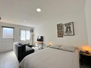 a white bedroom with a bed and a chair at Charmant studio in Plailly