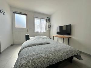 a bedroom with a bed and a flat screen tv at Charmant studio in Plailly
