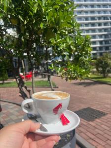 a person holding a cup of coffee on aucer at Квартира у моря с бассейном in Batumi