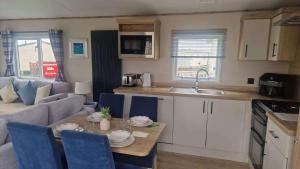 a kitchen and living room with a table and blue chairs at 3 Bed - Sleeps 8 - Family & Pet Friendly in Skegness +9 photos