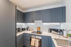 a kitchen with blue cabinets and a sink at Luxury 2BR Apartment I Sleep 8 I Direct to Wembley & Euston in Hatch End