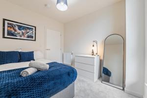 a white bedroom with a blue bed and a mirror at Luxury 2BR Apartment I Sleep 8 I Direct to Wembley & Euston in Hatch End