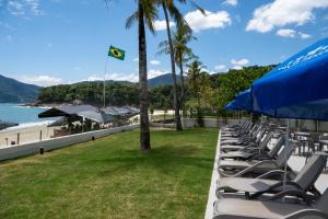a row of chairs and umbrellas next to the beach at Beach Hotel Paúba in São Sebastião