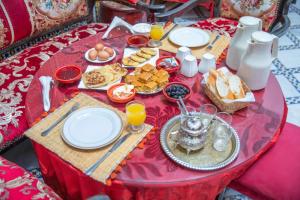 a red table topped with breakfast foods and orange juice at Riad Iline fes in Fez +92 photos