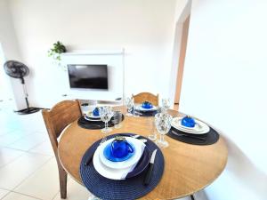 a wooden table with blue and white plates and glasses at Apartamento com varanda e VISTA para RUA, TV e 2 suítes in Teixeira de Freitas