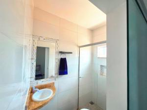 a bathroom with a sink and a shower at Apartamento com varanda e VISTA para RUA, TV e 2 suítes in Teixeira de Freitas +27 photos