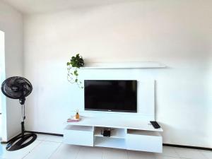 a living room with a tv on a white wall at Apartamento com varanda e VISTA para RUA, TV e 2 suítes in Teixeira de Freitas