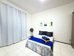 a bedroom with a bed with a blue blanket at Apartamento com varanda e VISTA para RUA, TV e 2 suítes in Teixeira de Freitas