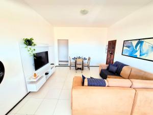 a living room with a couch and a tv at Apartamento com varanda e VISTA para RUA, TV e 2 suítes in Teixeira de Freitas