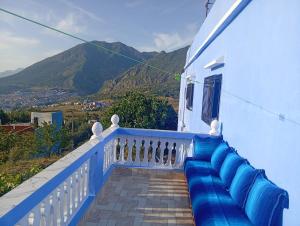 a balcony with a blue bench with mountains in the background at Dar Salima in Chefchaouen