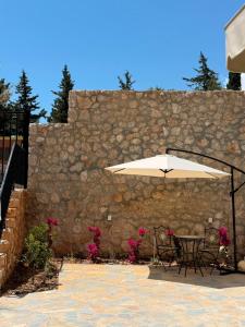 a table and chairs under an umbrella next to a stone wall at Piknik Suites in Dhërmi