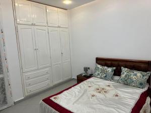 a bedroom with a bed with white cabinets at Appartement in Jijel