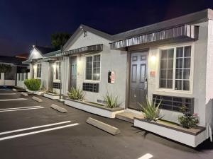a white house with plants in a parking lot at Scenic Motel - El Monte in El Monte +17 photos
