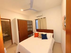 a bedroom with a white bed with blue and orange pillows at Cabaña Costa Azul 2 in Coveñitas