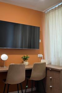 a desk with two chairs and a television on a wall at Velvet Studio in Zamość