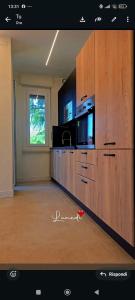 a large kitchen with wooden cabinets and a window at La casa del sole in Trofarello