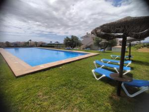 a pool with two blue chairs and an umbrella at Golf Paradise in Sant Jordi