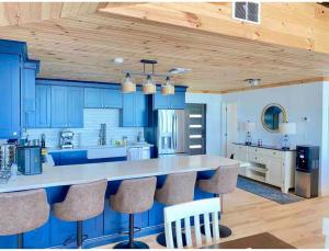 a kitchen with blue cabinets and a counter with chairs at Beach Villa Blue Bahamas in Mayaguana Island