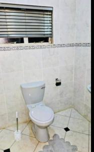 a bathroom with a white toilet and a window at The Vine House in Harare