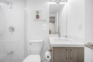 a white bathroom with a toilet and a sink at Bright 2BR Basement Apartment with Free Parking in Toronto +22 photos