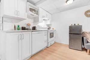 a white kitchen with white cabinets and appliances at Bright 2BR Basement Apartment with Free Parking in Toronto