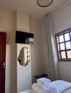 a bedroom with a bed and a mirror and a window at Vila Maytrea Chalés in Alto Paraíso de Goiás