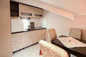 a kitchen with a table and chairs and a kitchen with a refrigerator at D apartmani in Sremska Kamenica