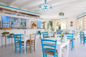 a dining room with white tables and blue chairs at PALMASERA CHARMING - Rooms & Suites in Cala Gonone +70 photos