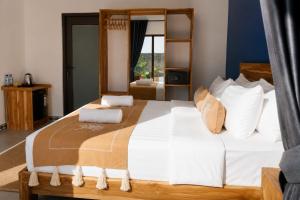 a bedroom with a large bed with white sheets at Luciana Hotel in Labuan Bajo