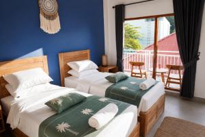 two beds in a room with a balcony at Luciana Hotel in Labuan Bajo