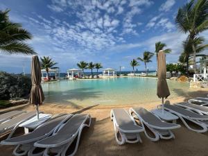 a pool with chairs and umbrellas on a beach at Penthouse In Tracadero Oceanfront Infinity Pool in La Laguna