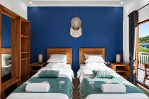 two beds in a room with a blue wall at Luciana Hotel in Labuan Bajo