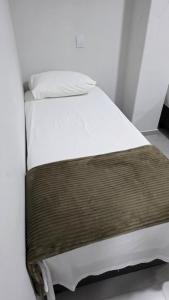 a bed with white sheets and a brown blanket at Trilhas do Araguaia in Aruanã +9 photos