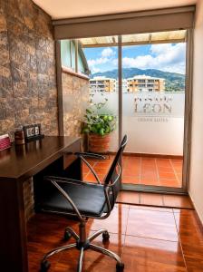 a office with a desk and a chair in front of a window at Hotel Posada Leon in Pasto