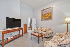 a living room with two couches and a flat screen tv at Ruawai Post Office Accommodation in Ruawai