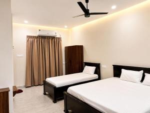 a bedroom with two beds and a ceiling fan at JK Suites in Rāmachandrapuram